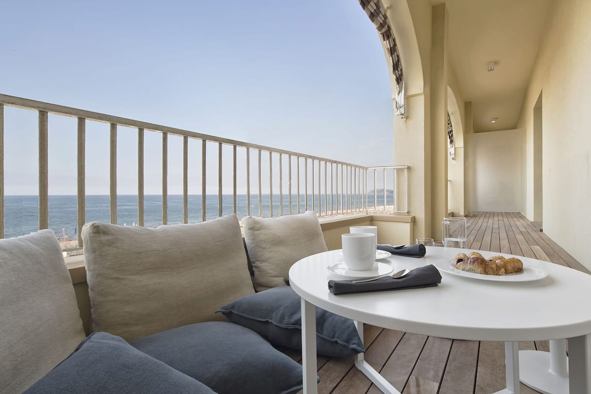 Un balcon avec une table blanche, une assiette de nourriture et une tasse.