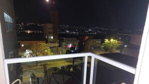 A balcony with a glass railing, a table, and chairs.