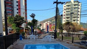 Una piscina con plataforma de baldosas, rodeada por una valla negra.