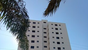 Un edificio de varios pisos con fachada de tejas, entrada porticada y cielo despejado al fondo.