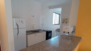 Una cocina con armarios blancos, encimera de granito y horno empotrado.