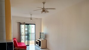 Amplia sala de estar con una encimera de cocina, un sofá rojo y un ventilador de techo.