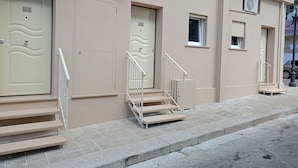 A building with multiple doors, a staircase, and air conditioning units.
