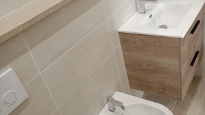 A modern bathroom with a toilet, bidet, and sink.