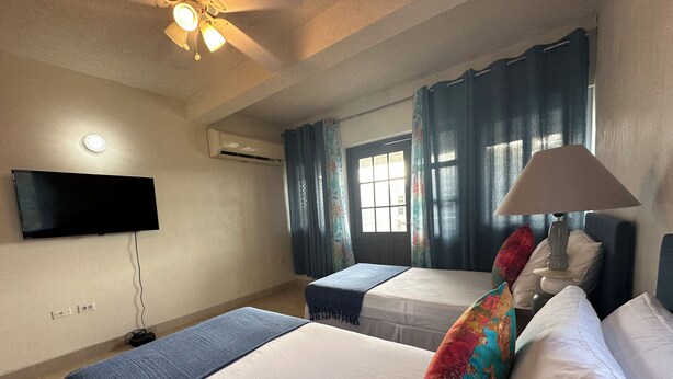 Une chambre d’hôtel avec un lit, un bureau, un téléviseur fixé au mur et une fenêtre avec des rideaux.