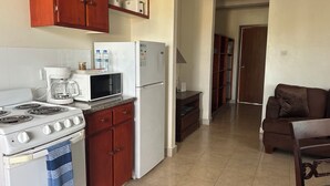 Une cuisine compacte équipée d’une cuisinière, d’un four à micro-ondes, d’un réfrigérateur et de meubles de rangement en bois.
