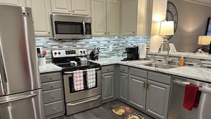 A modern kitchen with stainless steel appliances, a tiled backsplash, and a wooden floor. - Georgia Dawg House! Game weekend, business travel, this condo has it all!  (Athens)