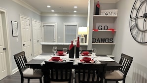 A dining room with a rectangular table set for four, surrounded by dark wooden chairs with cushioned seats. - Georgia Dawg House! Game weekend, business travel, this condo has it all!  (Athens)