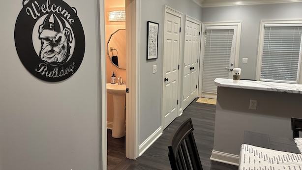 A hallway with a welcome sign, a bathroom, and a dining area with a table and chairs. - Georgia Dawg House! Game weekend, business travel, this condo has it all!  (Athens)