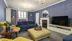 Ein Wohnzimmer mit einer Couch, einem Hocker und einem Fernseher.
