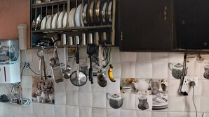 Une cuisine équipée d’un distributeur d’eau, d’ustensiles suspendus, ainsi que d’une variété de plats et d’ustensiles de cuisine.