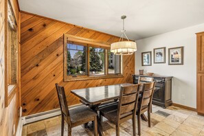 A dining area with a wooden table and chairs, a chandelier, and framed pictures on the wall. - Phoenix 2-Bedroom Condo – Comfort, Convenience, and Steps from the Slopes! (Steamboat Springs)