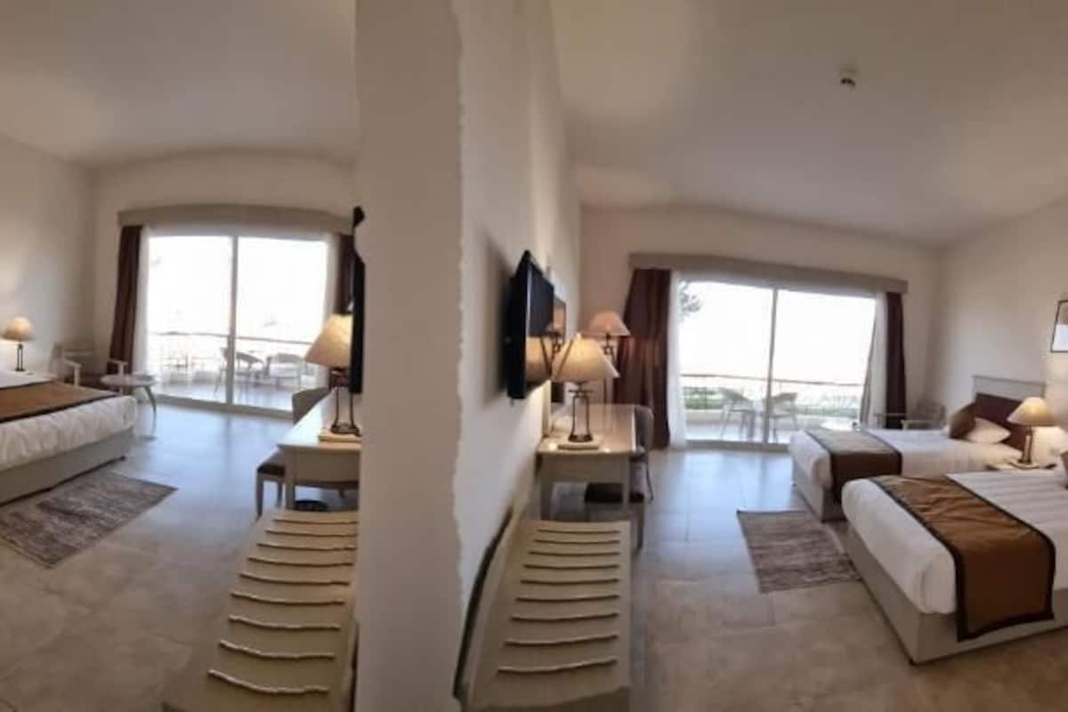 Une chambre d’hôtel spacieuse, dotée d’un grand lit, d’un bureau et d’un balcon avec vue.