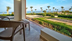 A balcony with wicker furniture overlooking a landscaped garden and a beach view. - Amarina Queen Resort & Aqua Park Marsa Alam (Marsa Alam)
