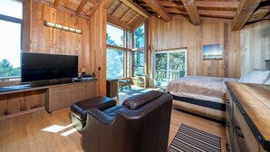 L’intérieur d’un chalet en bois, avec une grande télévision, un canapé, un lit et un bureau.