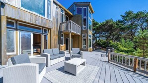 Une terrasse en bois avec des meubles d’extérieur, un balcon et une vue sur les arbres.