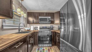 Una cocina moderna con electrodomésticos de acero inoxidable, armarios de madera y horno empotrado.