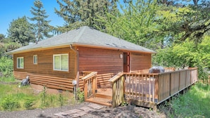 Una cabaña de madera con terraza, rodeada de árboles.