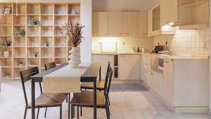 Una cocina moderna con armarios de madera, una mesa de comedor con sillas, y una estantería empotrada con plantas en macetas.