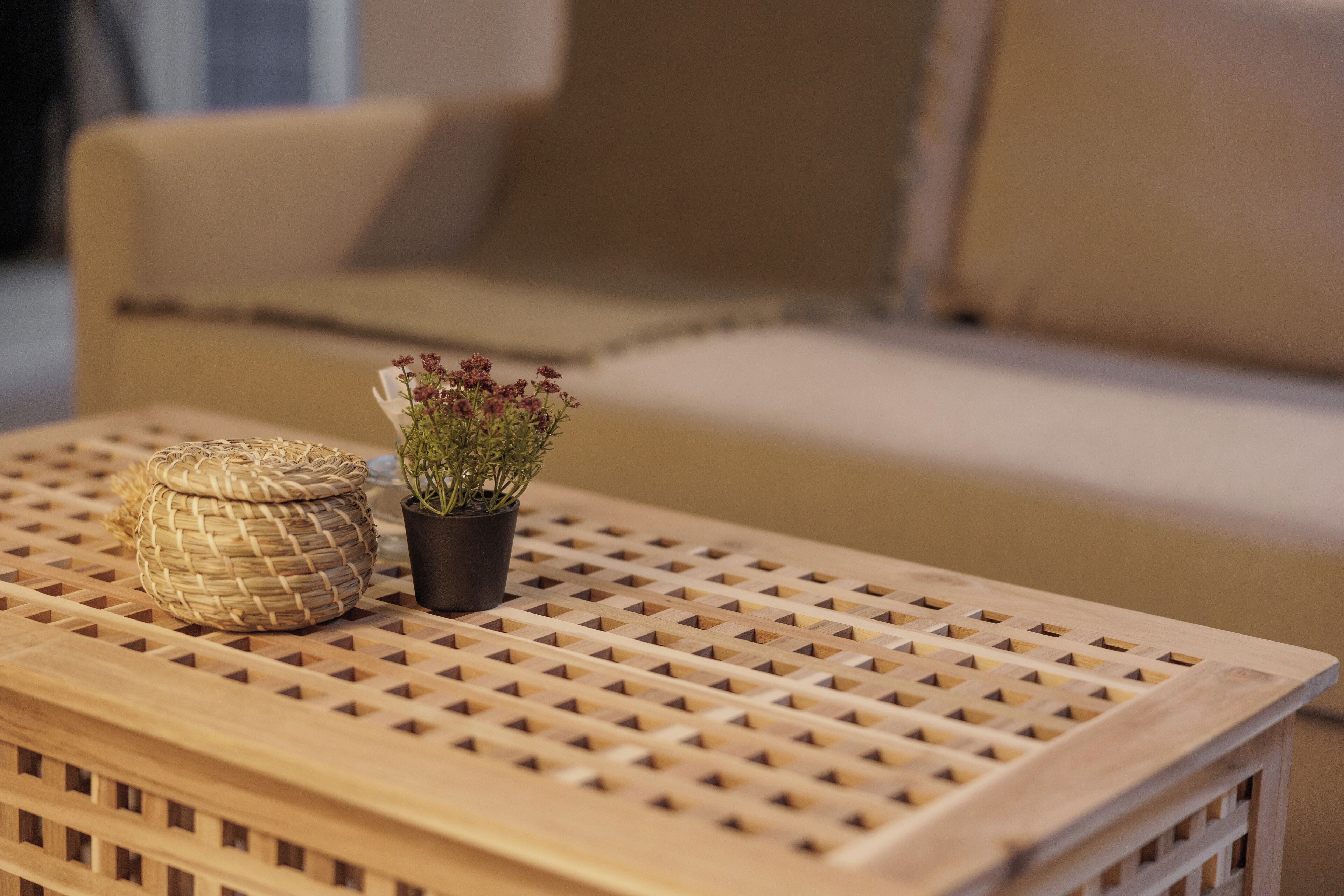 A wooden table with a woven basket and a potted plant.