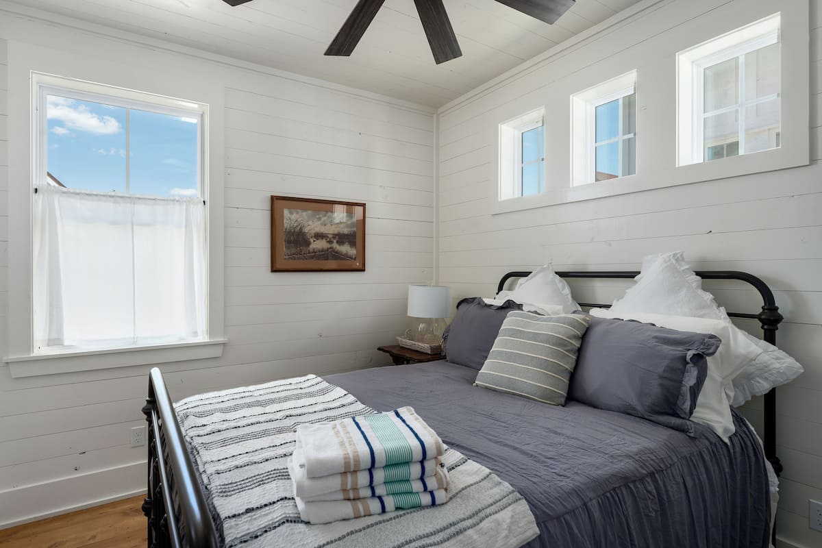 A bedroom with a bed, a nightstand, a lamp, and a window.