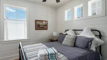 A bedroom with a bed, a nightstand, a lamp, and a window.