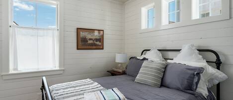 A bedroom with a bed, a nightstand, a lamp, and a window.