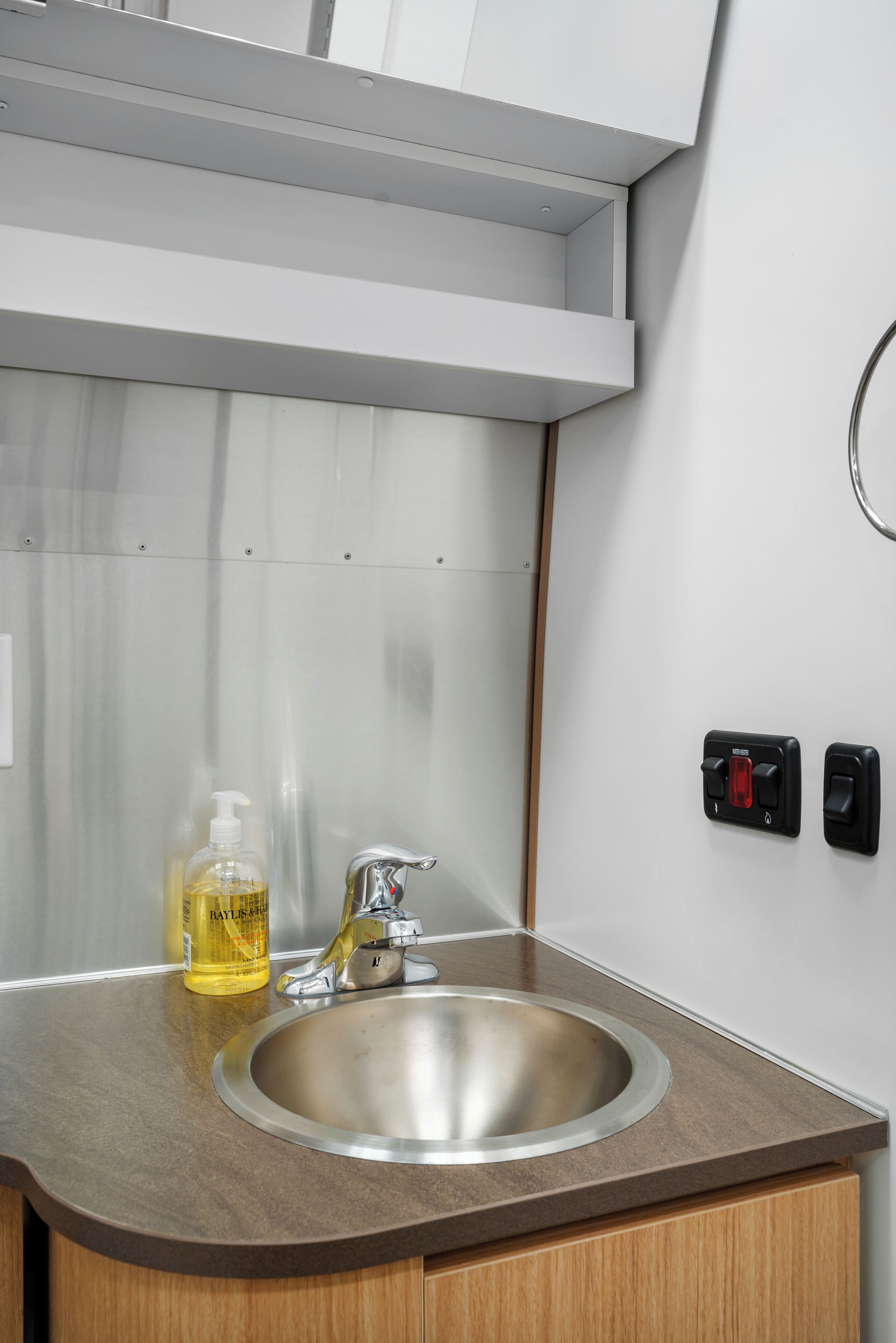 Une salle de bain équipée d’un lavabo en acier inoxydable, d’un distributeur de savon et d’un porte-serviettes.
