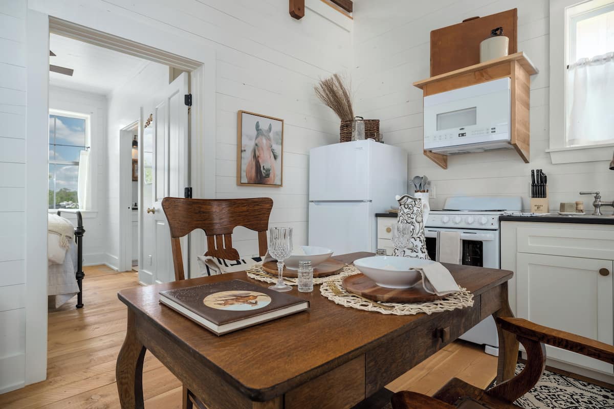 A kitchen with white cabinets, a wooden table, and a refrigerator.