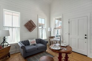 A cozy living room with a grey sofa, a dining table set for two, and a white door.