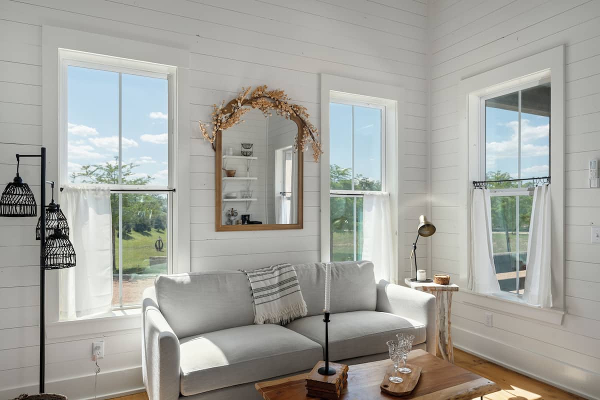 A cozy living room with a grey sofa, a wooden coffee table, and a mirror with a decorative arch.