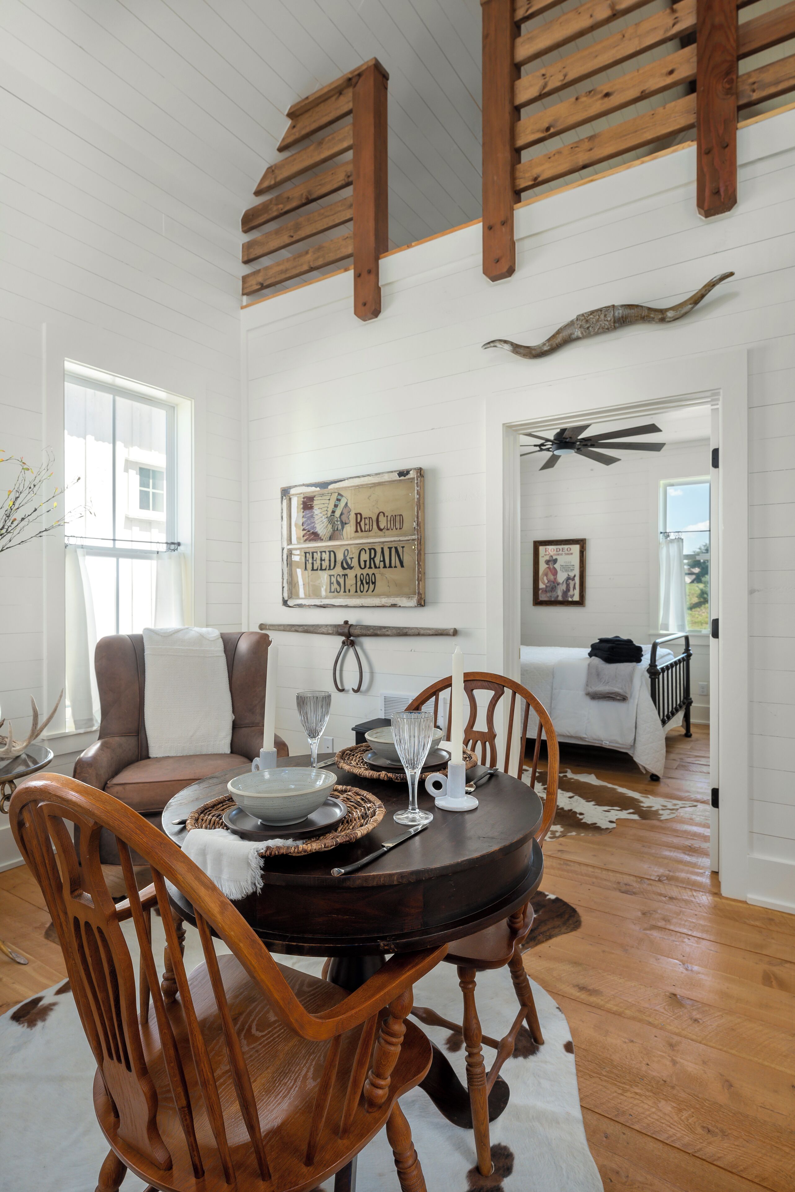 A dining area with a wooden table, chairs, and a rustic decor including a cowhide rug and a wooden ceiling beam.