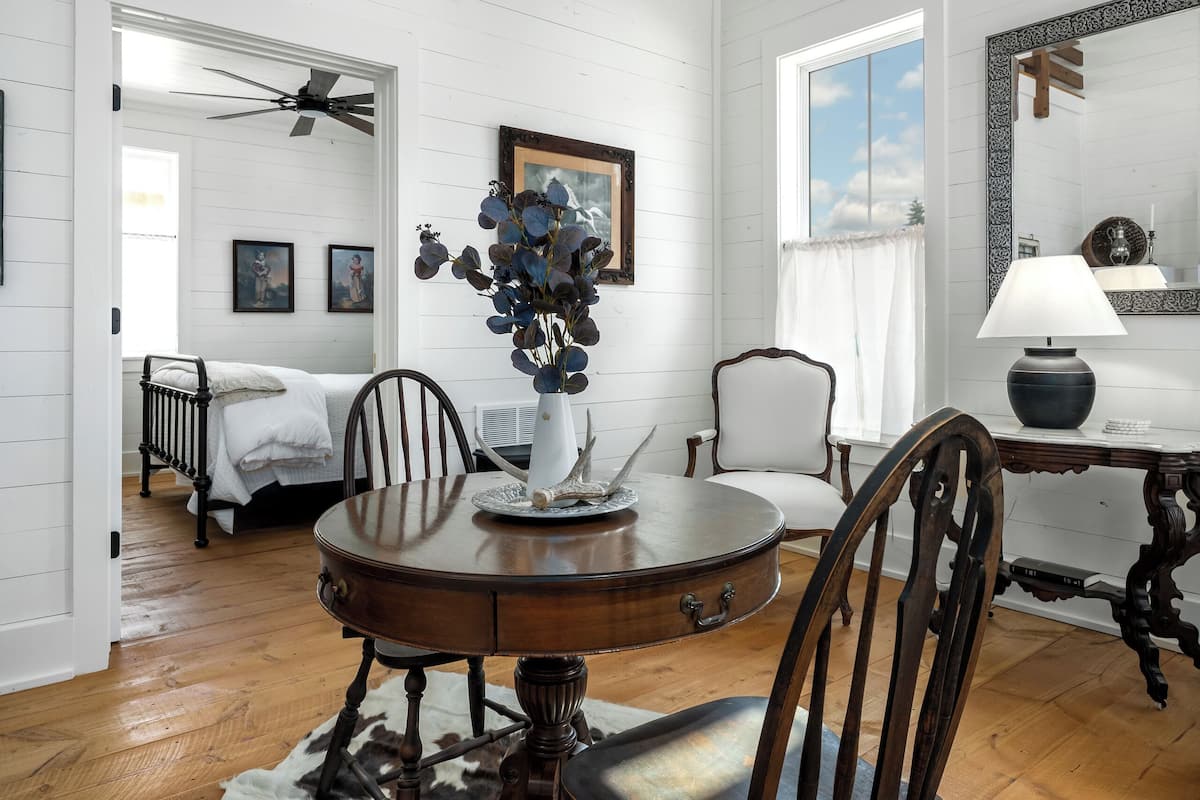 A dining area with a wooden table, chairs, a cowhide rug, and a vase with flowers.