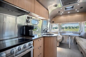 A compact kitchen with a stove, sink, and a small dining area with a table and bench.