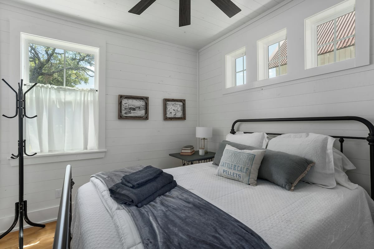 A bedroom with a bed, a nightstand, a lamp, and two framed pictures on the wall.