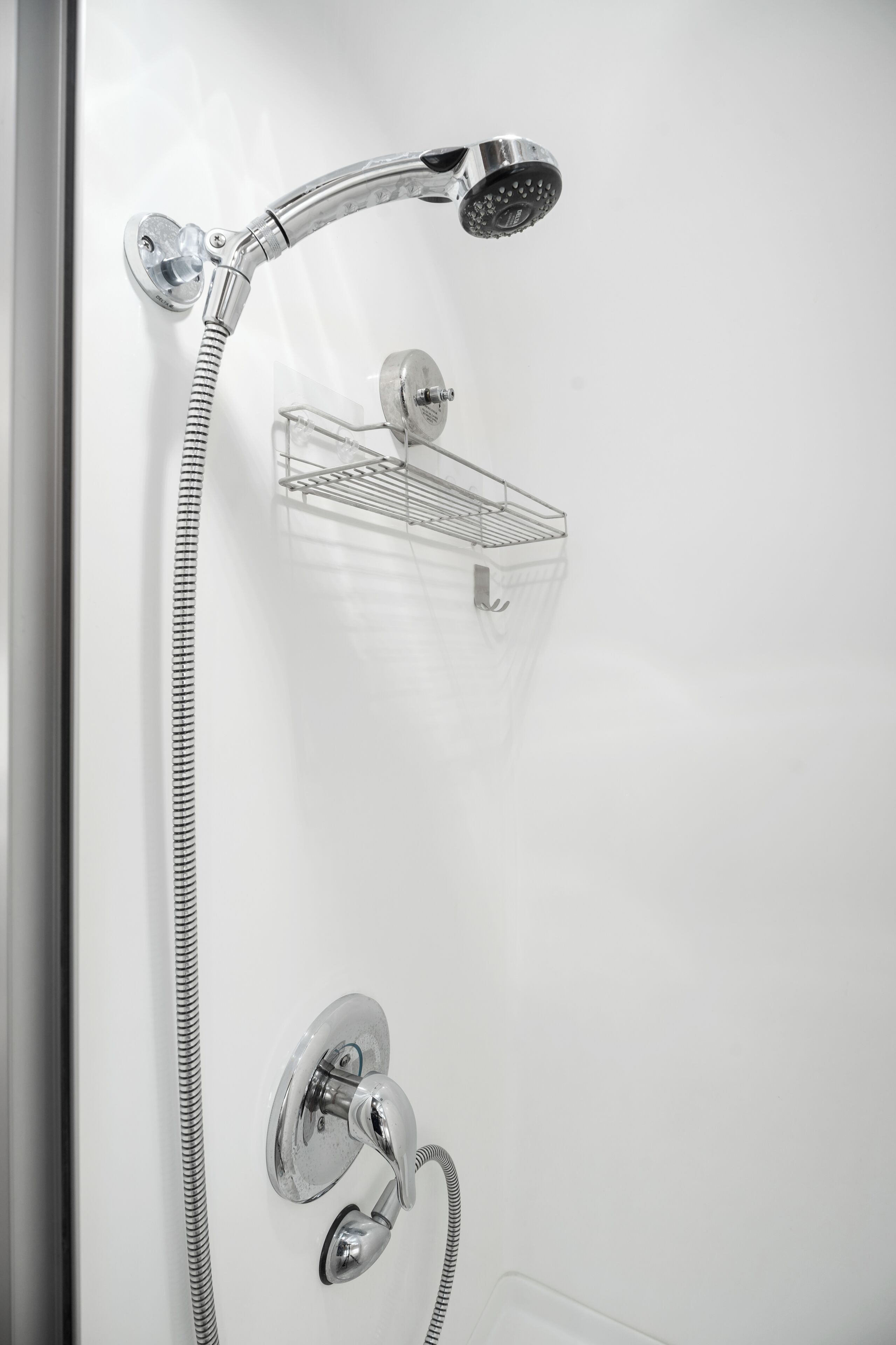 A shower with a handheld showerhead and a wall-mounted control.