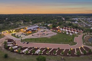 Vista aérea de uma área residencial com um edifício central rodeado por casas, um estacionamento e um jardim ajardinado.