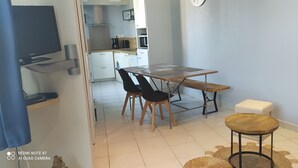 Un espacio habitable compacto con comedor, kitchenette y televisor.