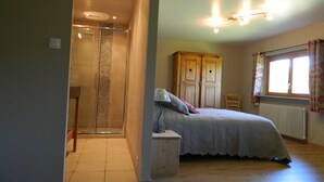 A bedroom with a bed, a wardrobe, a radiator, and a window with curtains.