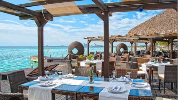 An outdoor dining area with tables set for guests, overlooking a body of water. - Hotel boca del mar Bocachica playa   (Boca Chica)