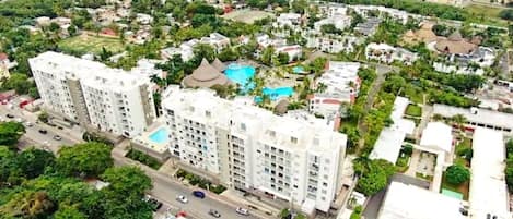A high-rise residential building with multiple balconies, a swimming pool, and a well-maintained garden area.