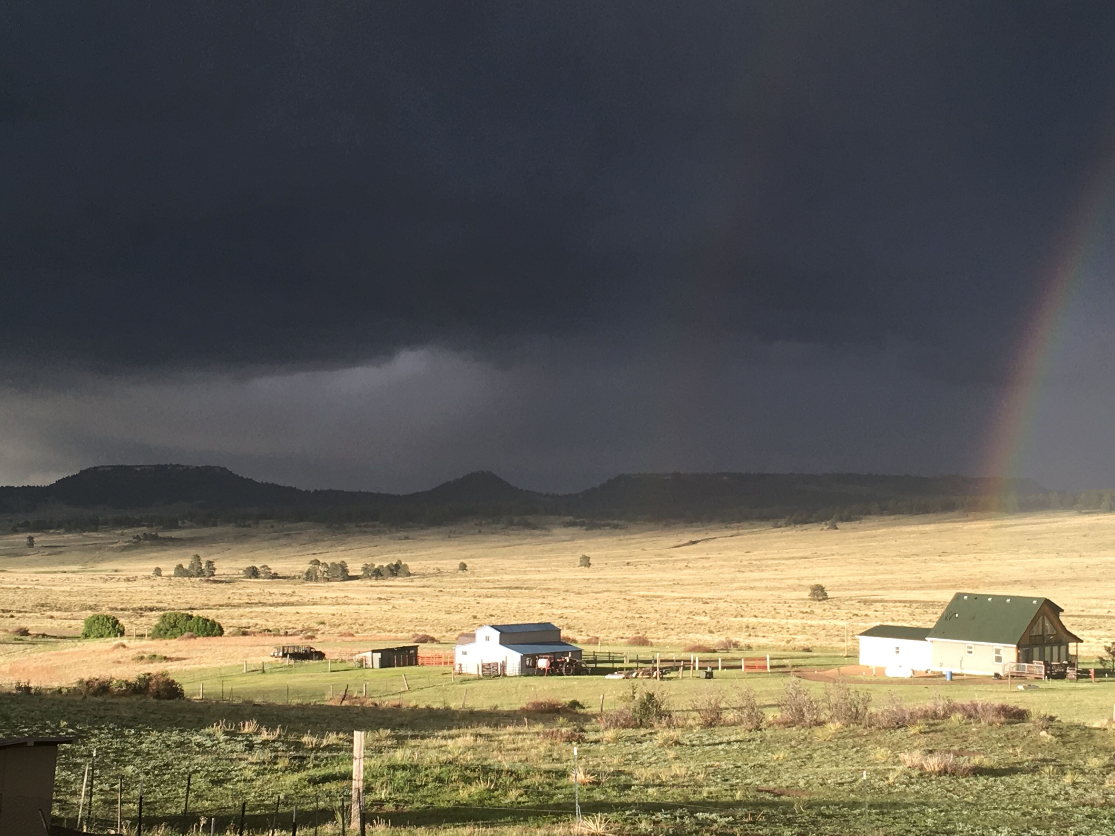 Paisaje rural con una casa de campo, graneros y un campo.