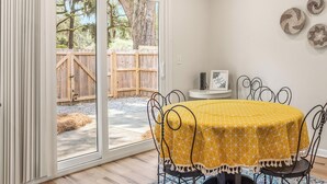 A dining area with a table covered by a yellow tablecloth, surrounded by metal chairs.