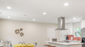 A modern kitchen with white cabinets, a stainless steel refrigerator, and a central island with stools.