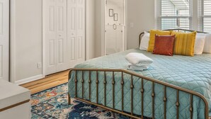 A bedroom with a bed, a ceiling fan, a walk-in closet, and a window with blinds.