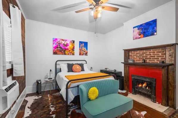 Un dormitorio con una cama, un sofá, una chimenea y dos obras de arte colgadas en la pared.