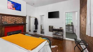 Una habitación con cama, chimenea, televisión y puerta que da a un balcón.