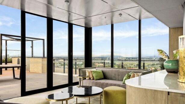 A modern living room with large windows, a sofa, a coffee table, and a small round table.