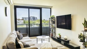 A modern living room with a sofa, a coffee table, a TV, and a bookshelf.