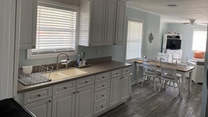 A kitchen with white cabinets, a sink, and a dining area with a table and chairs. - 3 blocks from Taylors Creek, 1 mile from Beaufort waterfront and boat ramp (Beaufort)